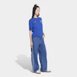 Pantalón de jean Adidas modelo Firebird, de corte recto y tiro medio. Presenta las icónicas tres franjas laterales en color blanco y cierre frontal con botón y cremallera.