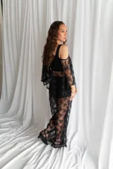 Blusa de tul negro translúcido con aplicaciones de perlas blancas dispersas, de corte amplio y mangas murciélago holgadas.