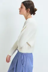 Sweater de punto gris con diseño de corazón blanco en el pecho, cuello redondo y mangas largas.