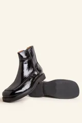 Bota corta de cuero vacuno con acabado charol brillante, diseño de punta cuadrada y suela de caucho con pequeña plataforma.