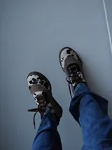 Zapatillas bajas de gamuza color marrón con detalles en cuero vacuno con estampado animal print de vaca.