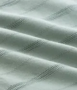 Bermuda recta de playa en color blanco roto, confeccionada en algodón texturizado con efecto de rayas verticales. Posee cintura elástica con cordón ajustable.