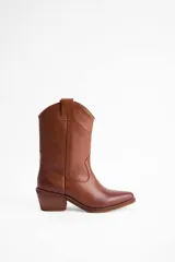 Bota de estilo western de caña media, confeccionada en cuero color suela, con taco cuadrado y punta ligeramente afinada.