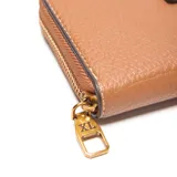 Billetera tipo fichero color habano confeccionada en cuero sintético (PU) con textura granulada. Presenta un cierre perimetral metálico, herrajes dorados y el logo metálico de la marca XL aplicado en el frente. Su interior está organizado con compartimentos para billetes, múltiples ranuras para tarjetas y un bolsillo central con cierre para monedas.