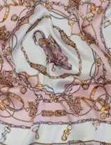 Pañuelo cuadrado de satén con estampado de cadenas y motivos ecuestres en tonos azul, blanco y dorado.