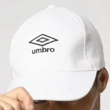Gorra clásica de seis paneles con visera curva, confeccionada en algodón blanco con el logo de la marca bordado en negro en el frente.