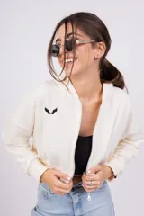 Campera corta color crema con cierre frontal, cuello mao y logo bordado en el pecho.