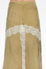 Falda midi de corte evasé en color beige, con aplicaciones de encaje blanco en forma de cruz y laterales. Cuenta con cierre invisible en la parte posterior.