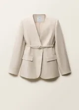 Blazer de lino color beige con diseño cruzado, cuello de pico y hombros estructurados. Incluye un cinturón ajustable con hebilla del mismo tejido y dos bolsillos laterales con solapa.