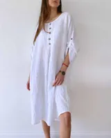 Vestido corto de lino en color blanco, con corte holgado, cuello redondo y cierre frontal parcial con botones. Presenta mangas tres cuartos con detalle de trabilla y botón.