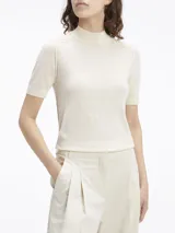 Sweater de lana merino color crema, de corte slim, cuello perkins y manga corta. Presenta detalles de puntadas en los hombros y ribetes de canalé en cuello, puños y bajo.