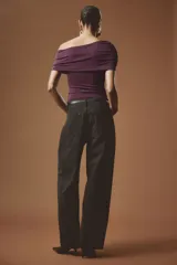 Top entallado de punto elástico color bordó, con diseño de hombros descubiertos, escote asimétrico drapeado y costuras fruncidas en un lateral.
