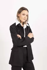 Blazer sastrero de corte clásico, color negro, con solapas tradicionales, bolsillos laterales con solapa y cierre frontal.