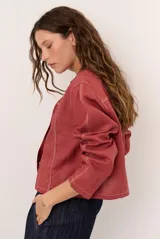Chaqueta de lino color beige, de manga larga, con cuello redondo y cierre frontal de botones a presión con solapa.