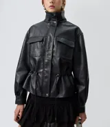 Campera Blue Steel de poliuretano efecto cuero color negro, de corte ligeramente amplio, con cuello alto estructurado, cierre frontal con botones a presión y tapeta superpuesta. Presenta bolsillos delanteros con solapa, cordón regulable en la cintura y mangas largas con puños abotonados.