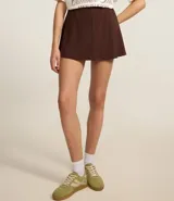 Short pollera de tiro alto en tejido Ponto Roma color marrón, con diseño estructurado, cintura elástica y recortes verticales que le otorgan un aspecto elegante.