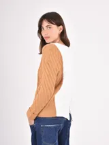 Buzo de tejido de punto con diseño tricolor, presentando un panel central en color blanco, una manga en color gris y la otra manga junto con el lateral en color tostado. Posee cuello redondo y puños acanalados.