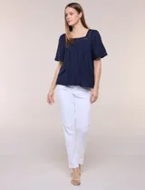 Blusa de corte holgado color marfil, confeccionada en mezcla de modal y algodón, con escote cuadrado y mangas cortas adornadas con detalles de puntilla calada.