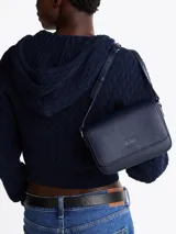 Cartera bandolera Tommy Jeans de color azul marino, de diseño estructurado con acabado liso, solapa frontal con cierre magnético y parche con el logo de la marca grabado en la parte delantera. Cuenta con correa ajustable para el hombro.