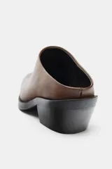 Zueco tipo mule de piel marrón con efecto desgastado, punta cuadrada y tacón bajo en bloque negro.