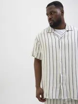 Camisa de manga corta con cuello resort y fit regular. Prenda liviana y fresca ideal para armar looks de verano con estilo. Diseñada para combinar comodidad y tendencia en un solo diseño. Cierre frontal con botones. Corte recto que aporta libertad de movimiento y un look relajado. Perfecta para usar abierta sobre una remera o sola para un estilo más pulido.