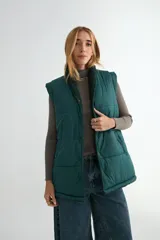 Chaleco acolchado de color verde oscuro, con cierre frontal de botones a presión y cuello con forro de sherpa a tono.