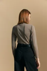 Polera de manga larga color marrón claro, con cuello alto y costura vertical decorativa en el frente.