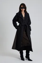 Trench largo bicolor negro y gris, de corte amplio, con cuello clásico, solapas, doble botonadura, cinturón y bolsillos laterales.