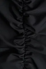 Top negro de punto elástico con breteles anchos que se cruzan en la espalda. Diseño ceñido con frunces en la parte delantera que crean un efecto drapeado.