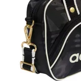 Bolso tipo bandolera Adidas Airliner, color negro con estampado geométrico sutil. Presenta el logo de la marca en el frente, detalles en blanco en los bordes y herrajes metálicos dorados. Incluye doble asa de mano y correa ajustable extraíble.