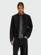 Campera negra de denim con cuello mao y cierre frontal. Diseño tipo trucker o cazadora, con puños y cintura ajustados con costuras visibles.