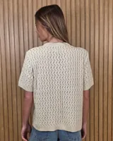 Cardigan calado de manga corta, tejido en punto con cierre frontal de botones y cuello redondo.