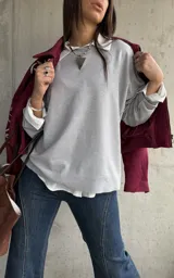 Sweater de punto color gris, de corte holgado y diseño de manga larga con costuras visibles en los hombros. Presenta cuello redondo y puños acanalados.