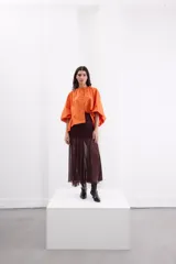 Camisa holgada de popelina de algodón con rayas verticales en tonos rosado, gris y blanco. Presenta cuello alto con volado, hombros caídos, mangas anchas abullonadas y cierre frontal con botones.