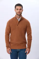 Buzo de punto color beige, con cuello alto y cierre frontal con cremallera y solapa de gamuza con botón. Presenta un tejido texturizado en el cuerpo y mangas lisas.