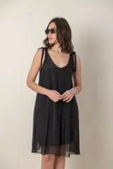Vestido corto de seda y viscosa en color negro, de calce suelto con tirantes finos que se anudan sobre los hombros y escote en V.