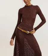 Cinturón estilo boho color tostado, con diseño de bordes ondulados y aplicaciones de tachas metálicas circulares. Cuenta con hebilla metálica de estilo western y múltiples perforaciones para ajuste.