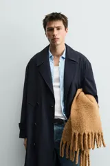 Trench de corte relajado confeccionado en tejido con viscosa, de color azul marino. Presenta cuello con solapas de muesca, cierre frontal de botonadura cruzada, mangas largas con puños ajustables mediante trabillas y bolsillos de vivo en la cadera. Incluye una abertura central en la espalda.