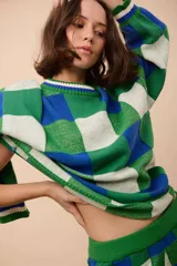 Buzo oversized de punto texturizado, con diseño a cuadros en tonos de verde, azul y blanco. Tiene cuello redondo y puños acanalados.