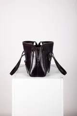 Cartera tipo bolso de mano y hombro de cuero color bordó, con diseño estructurado, doble asa corta y detalles de correas con hebillas metálicas en el frente.