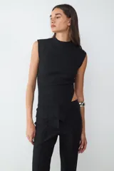 Top tejido sin mangas con diseño asimétrico, cuello subido y acabado en tricot texturizado. Presenta un calce ajustado que realza la silueta.