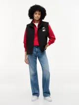 Chaleco negro con cuello chimenea, cierre de cremallera oculto con botones a presión y dos bolsillos laterales ribeteados. Presenta logos bordados en el pecho de Tommy Hilfiger y Cadillac Formula 1 Team.