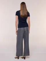 Remera básica de corte al cuerpo con textura acanalada, cuello redondo y mangas cortas. Presenta una pequeña placa metálica decorativa en el borde inferior.