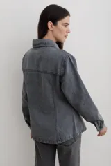 Chaqueta de denim color marrón, con corte entallado en la cintura, cierre frontal con botones metálicos y bolsillos superiores con solapa.