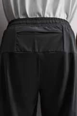 Pantalón negro de entrenamiento slim fit confeccionado en tejido técnico ligero y elástico con estructura. Cuenta con cintura elástica ajustable con cordón, bolsillos frontales y trasero con cierre de cremallera, y bajo ajustable con cremallera en laterales.