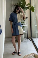 Vestido tejido a rayas horizontales en tonos beige y marrón, con cuello redondo y mangas cortas con ribete negro.