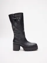 Bota bucanera de cuero vacuno wax color negro, con punta cuadrada, suela de goma con plataforma dentada y taco de madera. Presenta detalle de doble hebilla metálica en la parte superior de la caña.