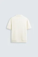 Polo de manga corta color verde oliva, con cuello solapa y abertura frontal tipo polo. Presenta una textura acanalada vertical y un calce regular.