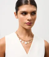Collar corto de cadena de eslabones medianos con baño dorado, decorado con múltiples dijes que incluyen corazones, perlas y símbolos místicos. Cuenta con cierre ajustable y extensor.
