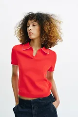 Top de punto color crudo, con cuello polo y escote en V. Cuenta con mangas cortas y detalle de puntilla con forma de onda en el cuello y los puños.